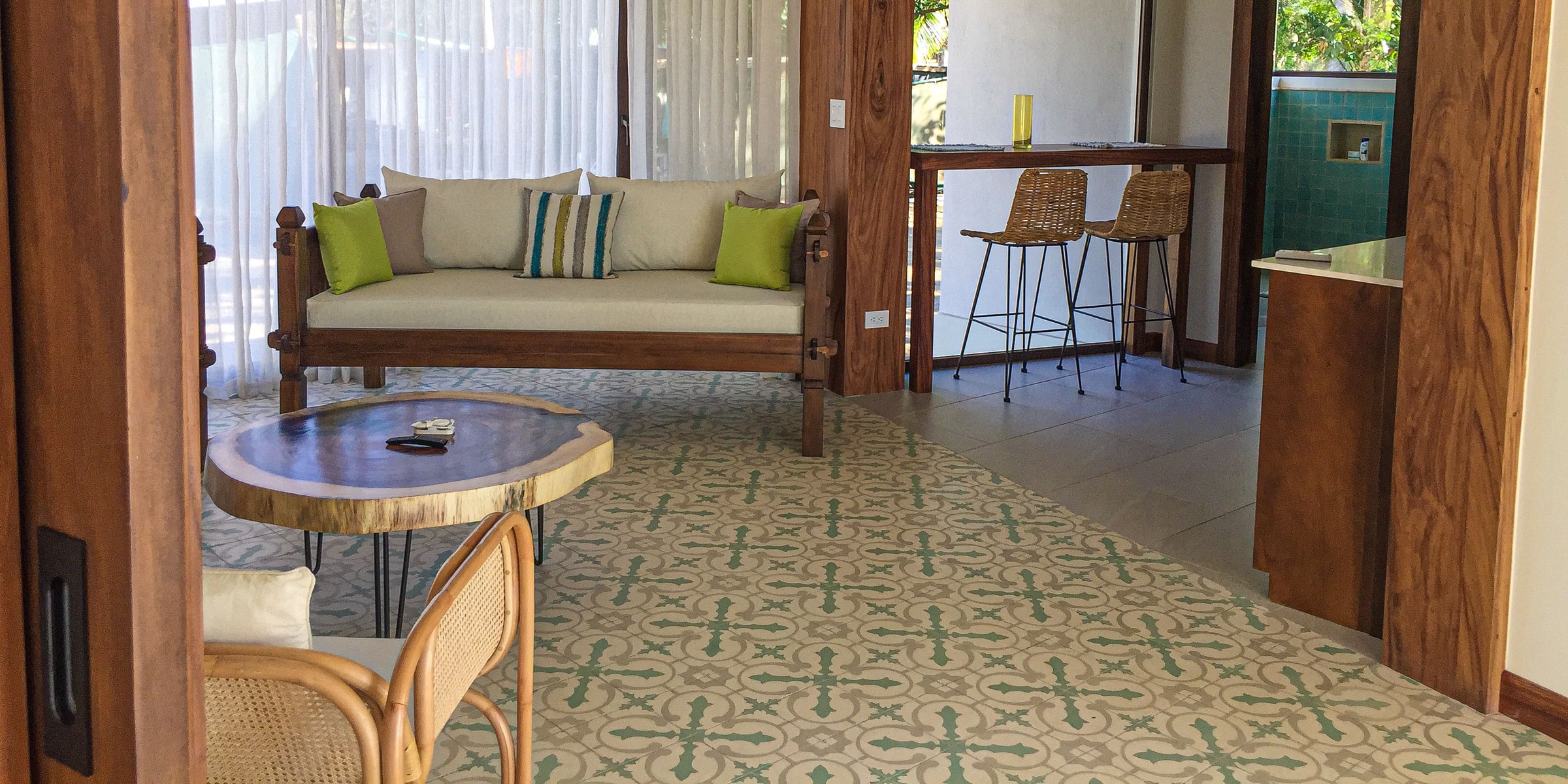 Villa lounge with a wooden daybed, green cushions and patterned cement tiles
